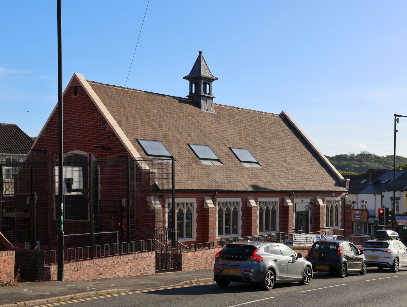 The rebuilt Double Six Youth Club on Scarsdale Road: red brick, a new tiled roof with skylights and a bell turret, with the netted games area beside it